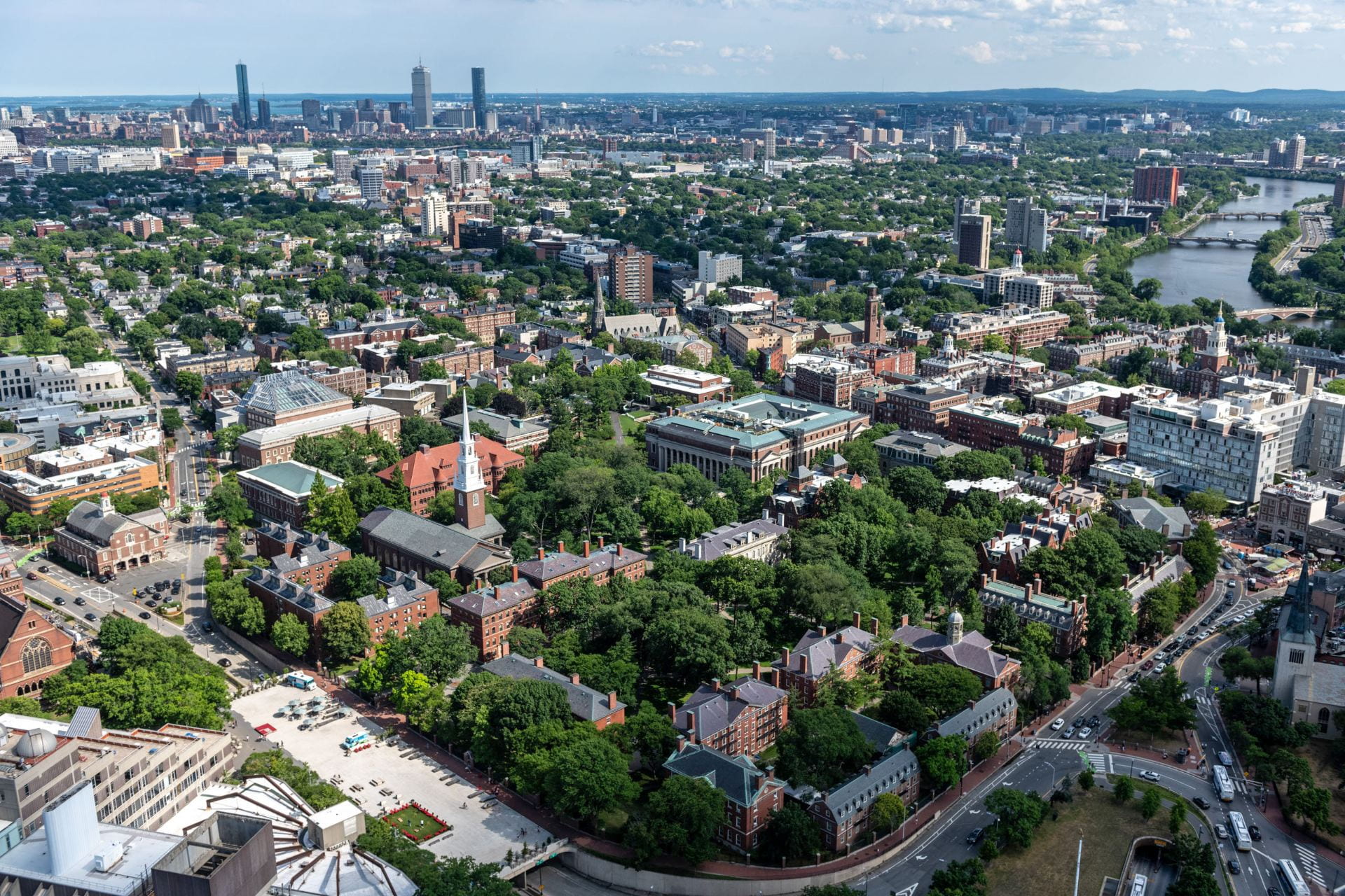 Image of tree filled Harvard Yard focused on Widener Library with views to the Charles River and the city of Boston.